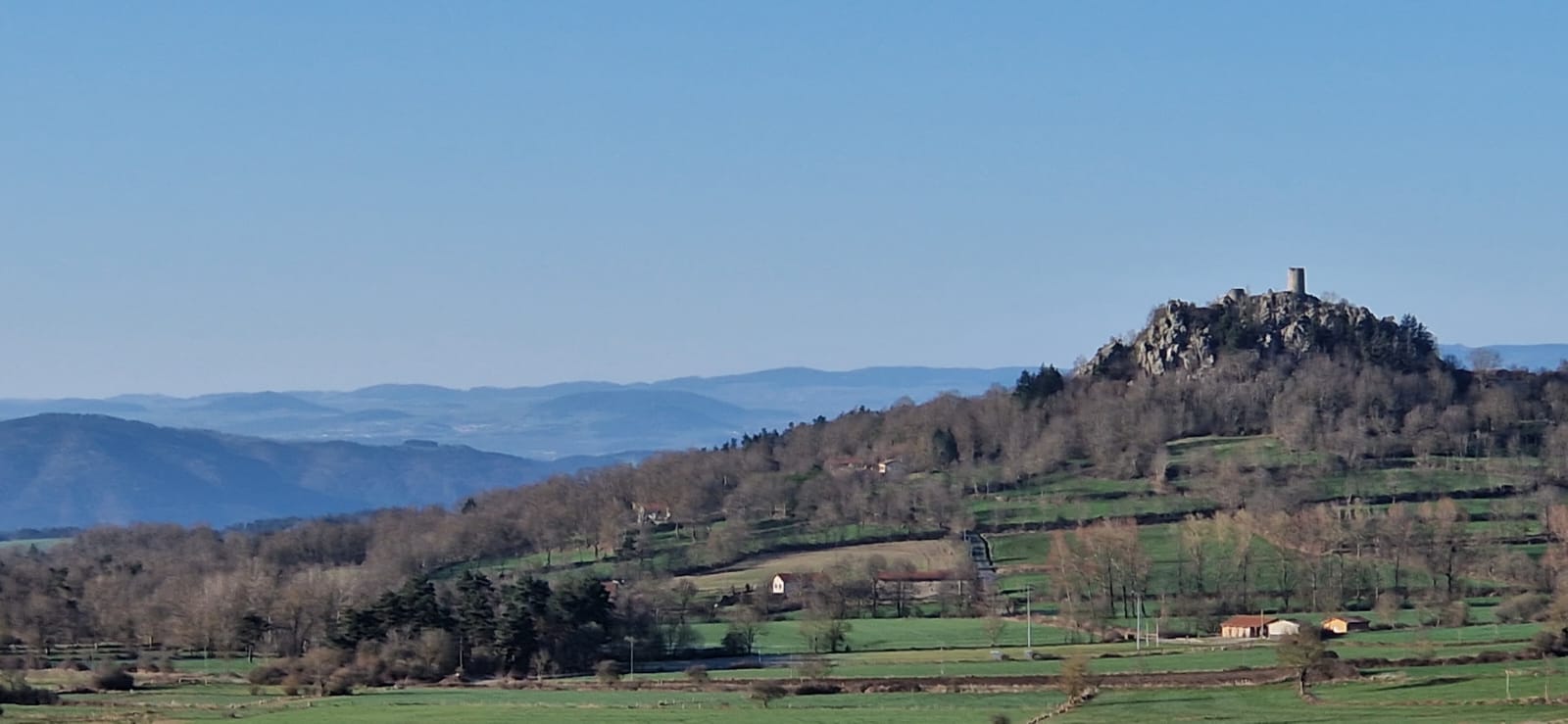 Vue panoramique illustrée de la Haute-Loire avec pont de pierre, chibotte en premier plan, village médiéval, châteaux perchés, et volcans en arrière-plan, dans un style peinture traditionnelle.